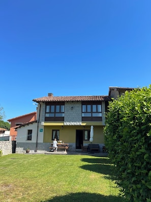 Ein zweistöckiges Gebäude mit Ziegeldach, Steinaußenwand und einer kleinen Terrasse mit Tisch und Stühlen.