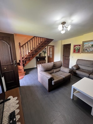A living room with a wooden staircase, two sofas, a coffee table, and a door.