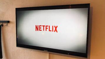 A flat-screen TV mounted on a wall displaying the Netflix logo.