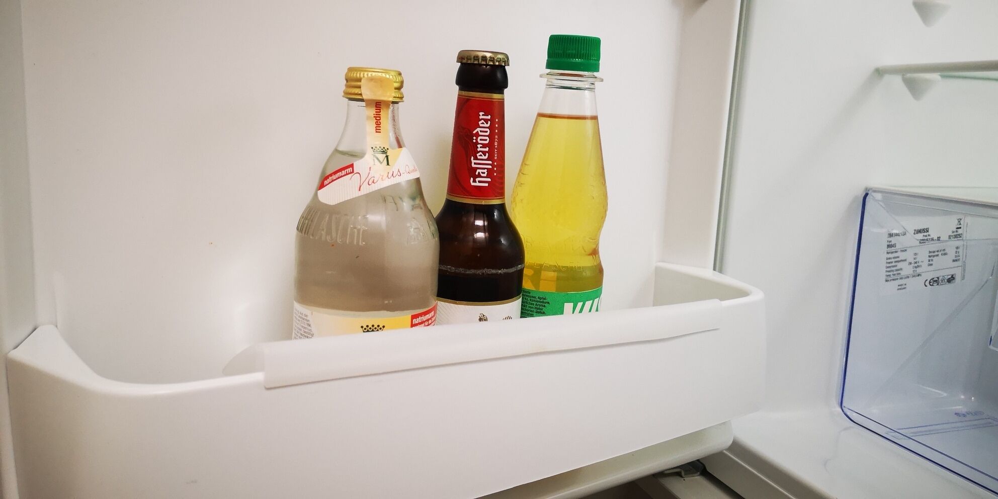 A refrigerator with three bottles of beverages.