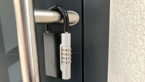 Un candado sujeto a un pomo metálico en una puerta.