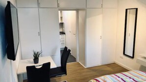 Un dormitorio con cama, escritorio, silla y armario.