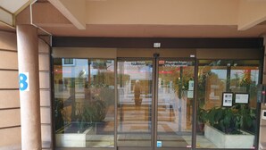 L’entrée d’un hôtel, avec des portes en verre, une enseigne portant le chiffre « 8 » et des plantes en pot.