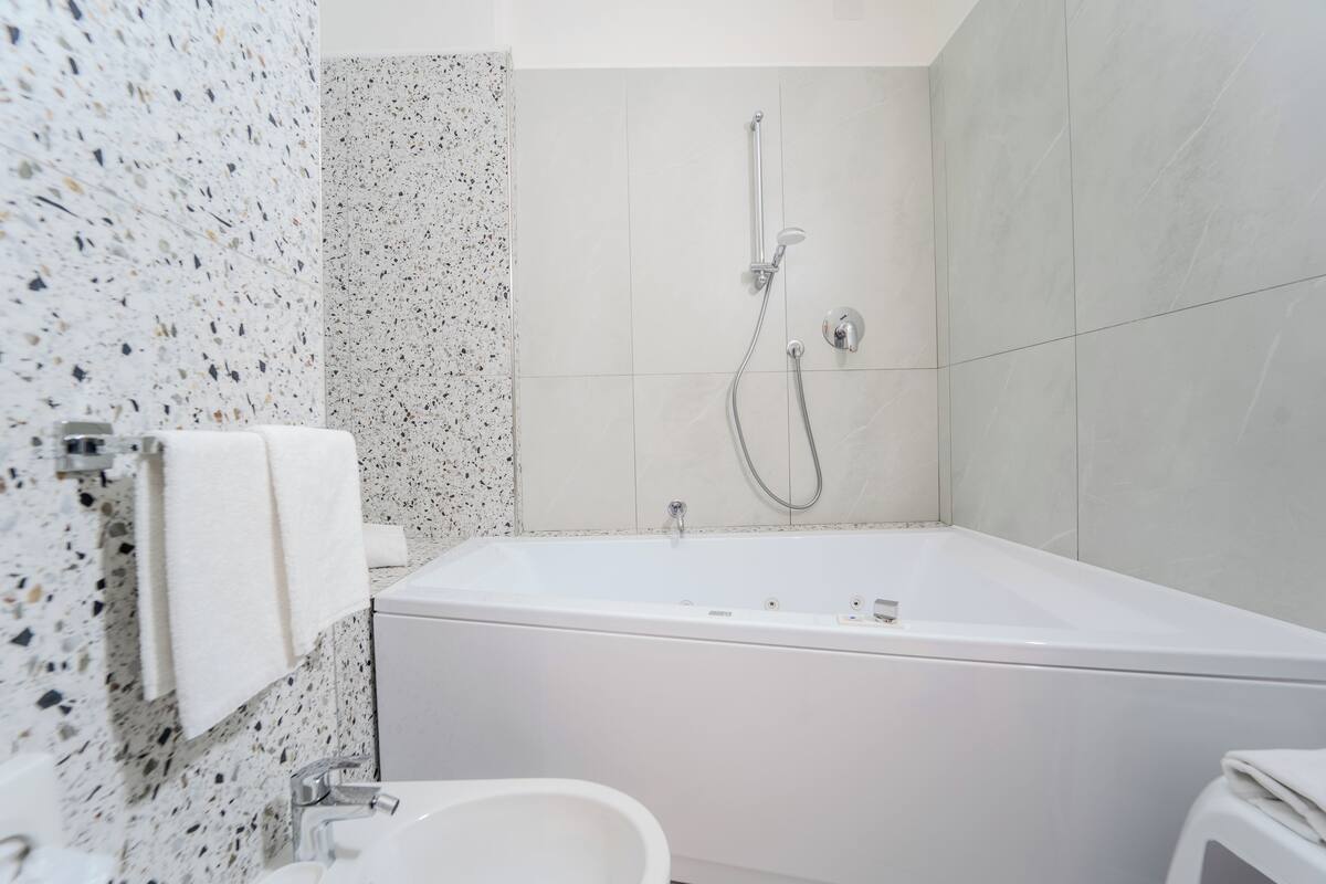 A modern bathroom with a freestanding bathtub, a showerhead, and a toilet.