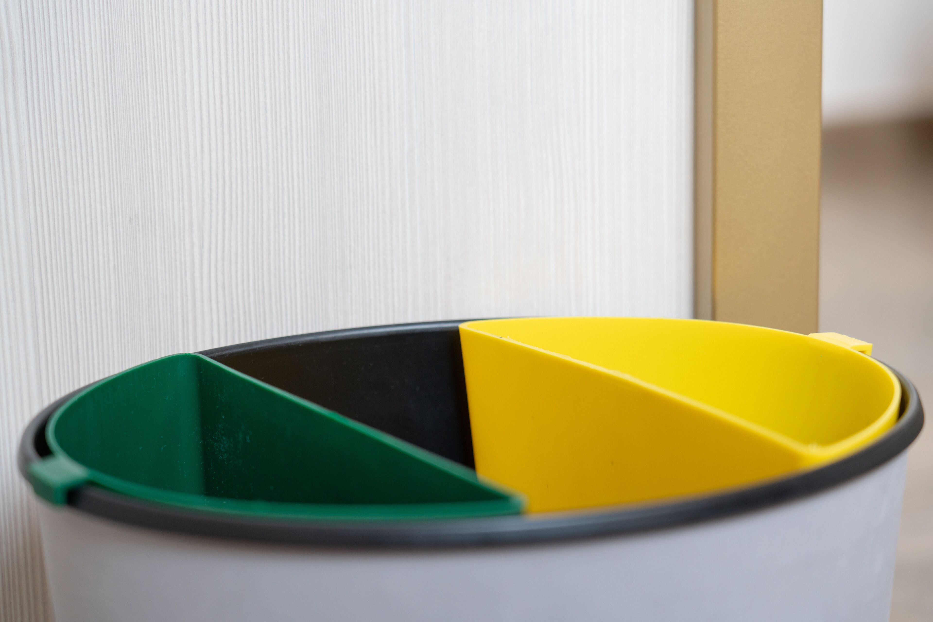 A trash can with a yellow and green lid.