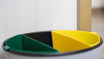 A trash can with a yellow and green lid.