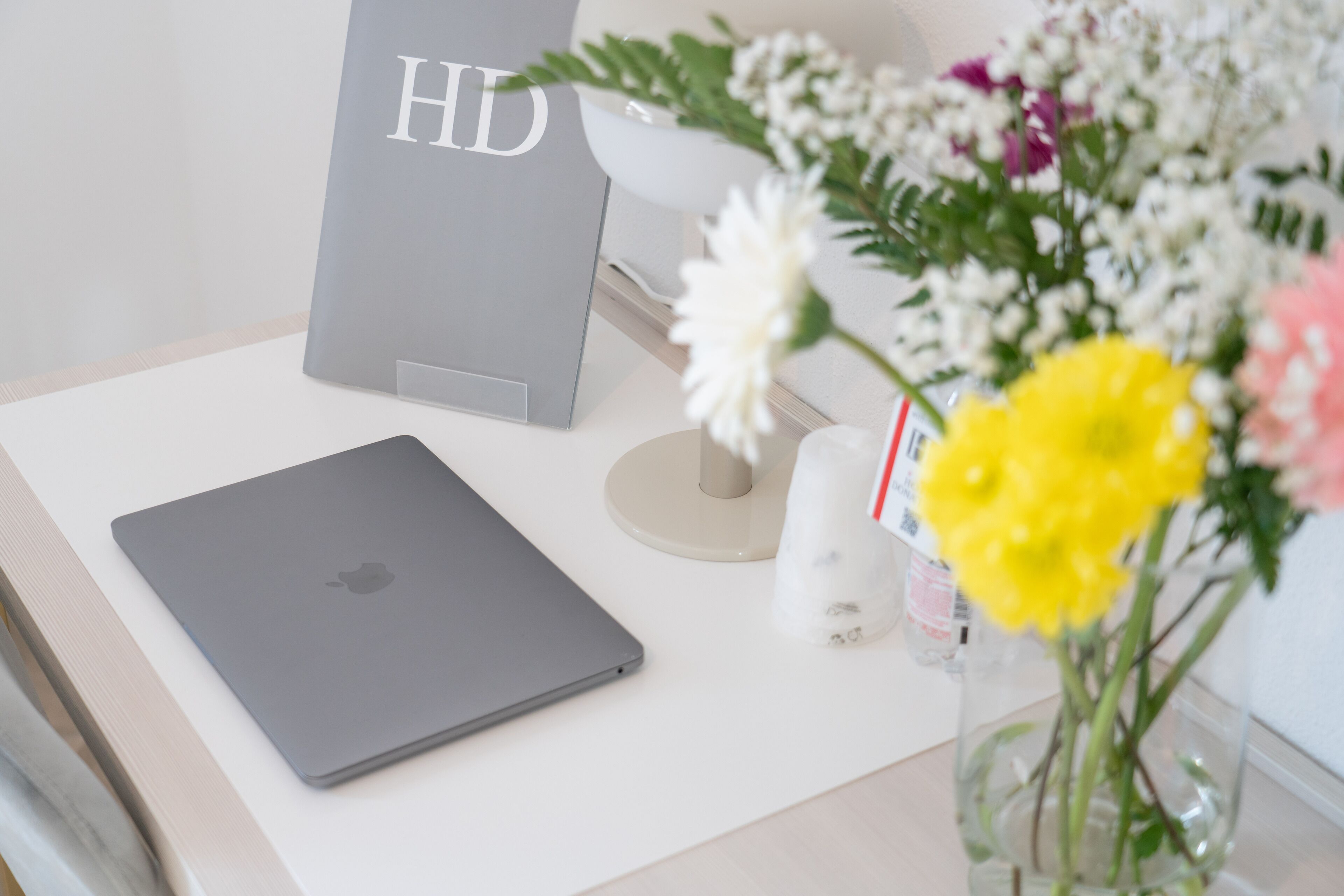 Un portatile su una scrivania con un bouquet di fiori e una scatola grigia con la scritta 