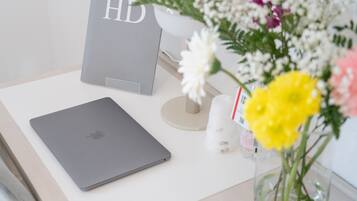 Un portatile su una scrivania con un bouquet di fiori e una scatola grigia con la scritta