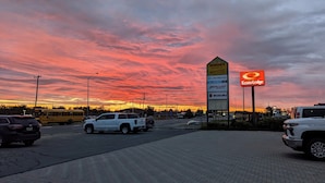 Een parkeerplaats met een bord voor Econo Lodge en een groot reclamebord met verschillende bedrijfsnamen.