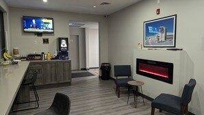 Een moderne hotelkamer met een keukenhoek, een zithoek met stoelen, een televisie en een open haard.