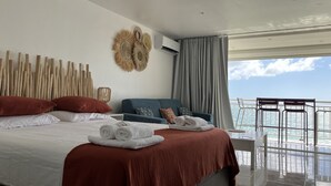 Habitació d'hotel moderna amb un llit gran, un balcó amb vista al mar i una obra decorativa a la paret.