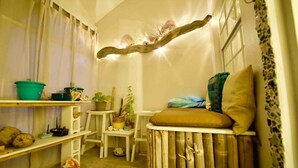 Une pièce chaleureuse au décor rustique, avec une étagère en bois ornée de plantes, un banc rembourré et un luminaire original.