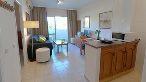 Una sala de estar moderna con sofá, mesa de centro y un comedor con una pequeña isla.