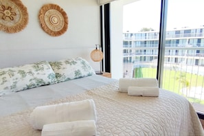 Une chambre d’hôtel avec un grand lit, deux éléments de décoration murale, un luminaire suspendu et une vue sur un bâtiment à l’extérieur.