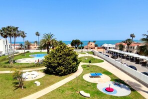 Un complexe hôtelier doté d’une piscine, de palmiers et offrant une vue sur la mer.