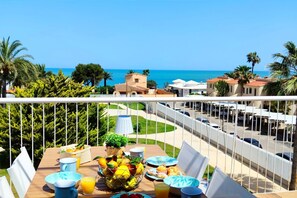 A balcony with a breakfast setup overlooking a coastal view.