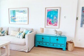 Un salon avec un canapé, un meuble turquoise et deux œuvres d’art encadrées accrochées au mur.