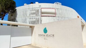 Moderni rakennus, jossa on kaareva julkisivu ja suuri, näkyvä logo, joka edustaa Denia Beach Residential -asuntoyhtiötä.