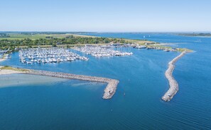 An aerial view of a marina with numerous boats docked, surrounded by water and greenery.