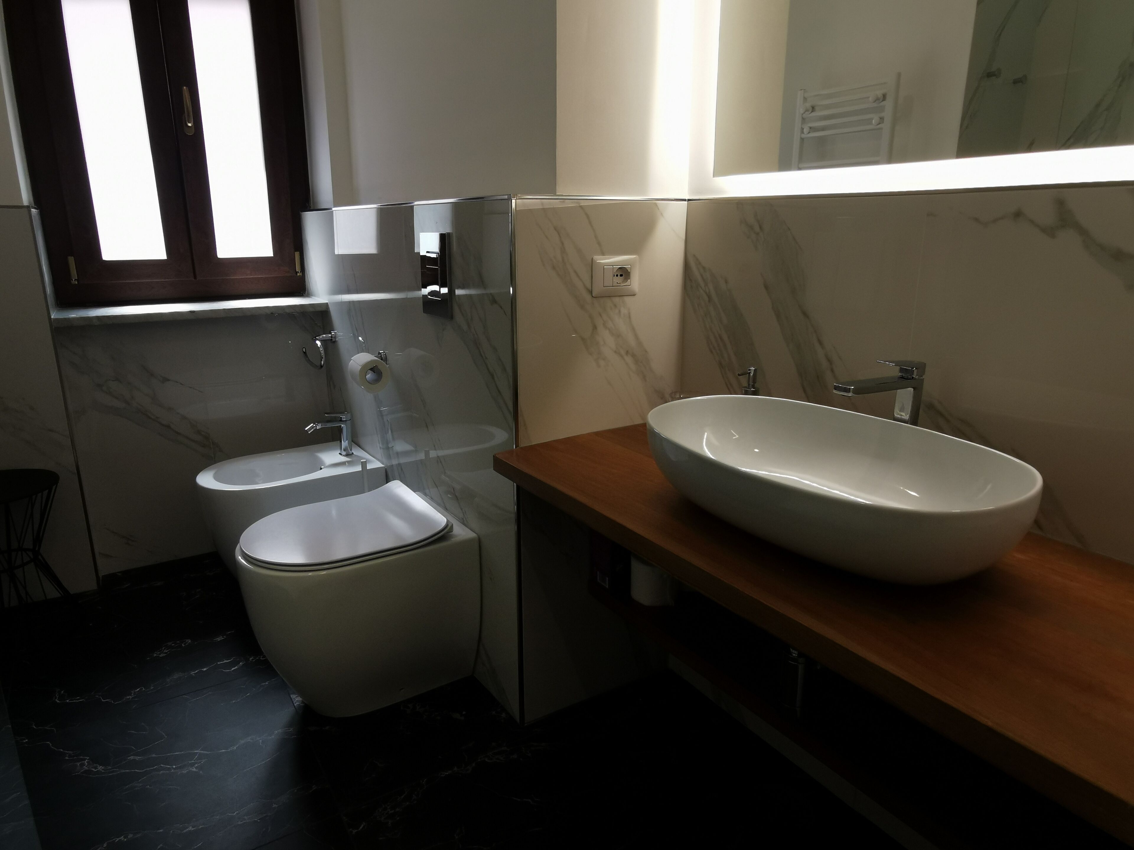 A modern bathroom with a toilet, sink, and mirror.