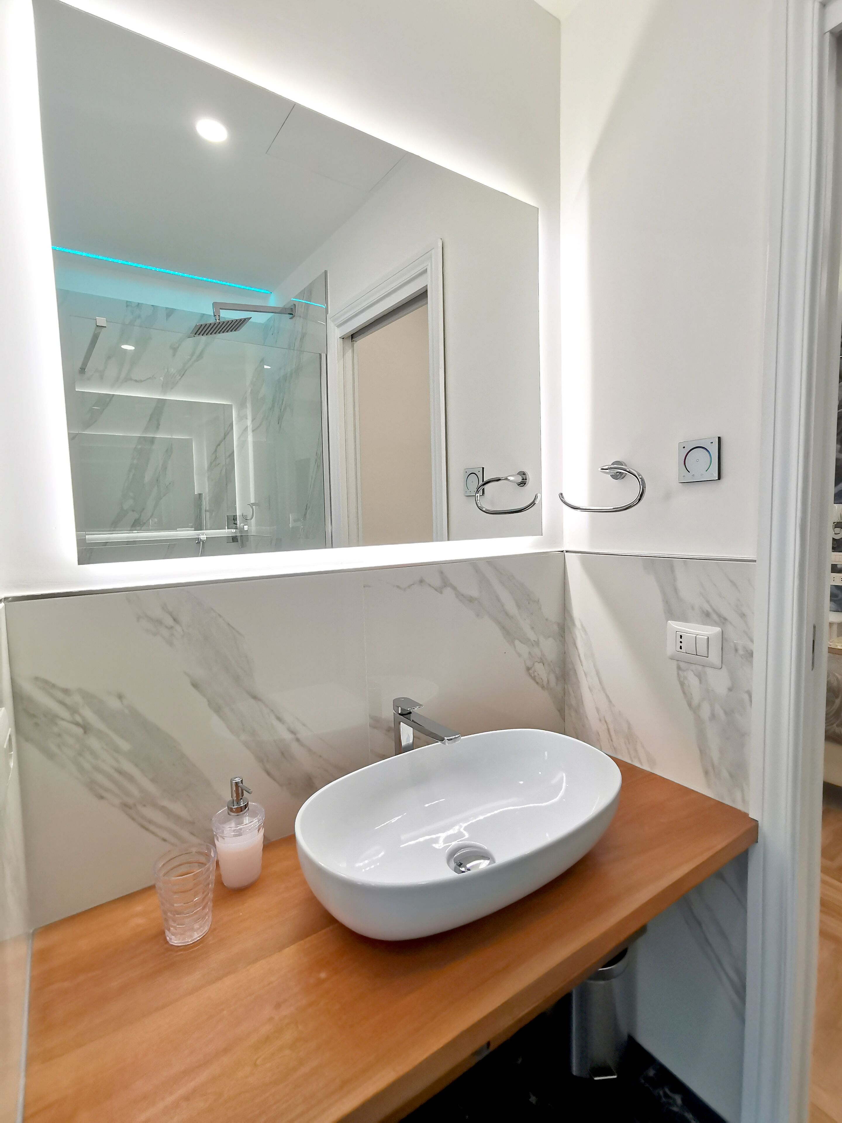 A bathroom with a marble vanity, a white sink, and a glass shower enclosure.