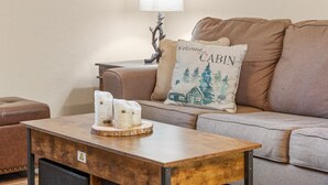 Un salon avec un canapé en cuir marron, une table basse en bois agrémentée d’objets décoratifs et une lampe.