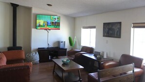 A living room with a television, a fireplace, a dining table, and leather chairs.