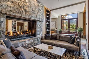 Cozy living area with a stone fireplace, comfortable seating, and large windows offering views of the surrounding landscape.