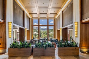 Enjoy a mountain view from the comfort of this interior space, featuring a high ceiling, large windows, and natural touches.