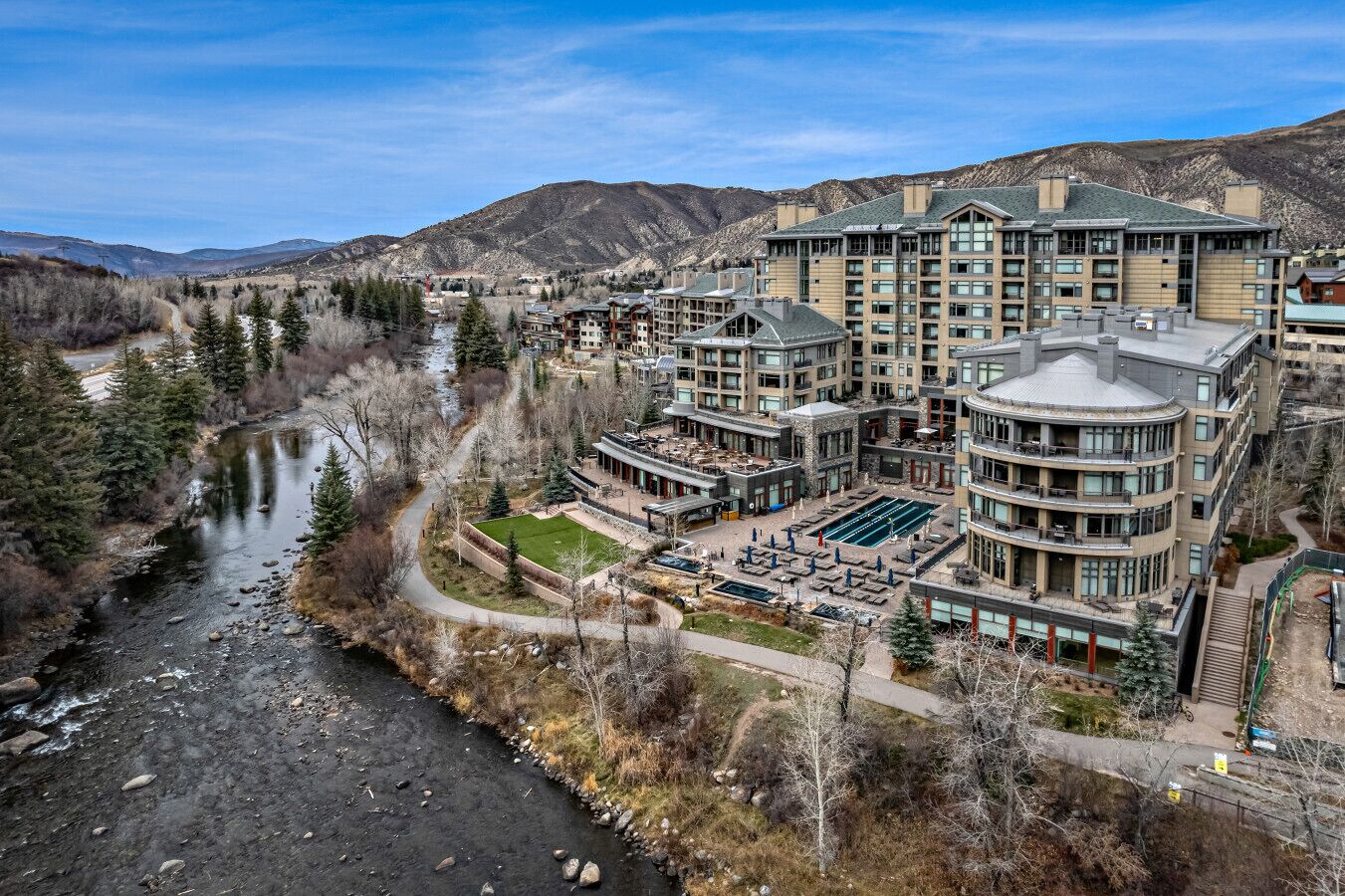 A hotel with multiple floors, a swimming pool, and a river nearby.