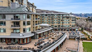 Un hotel con varios pisos, zonas de estar al aire libre y vistas a montañas.