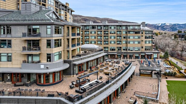 Un hôtel à plusieurs étages doté d’espaces extérieurs aménagés et offrant une vue sur les montagnes.
