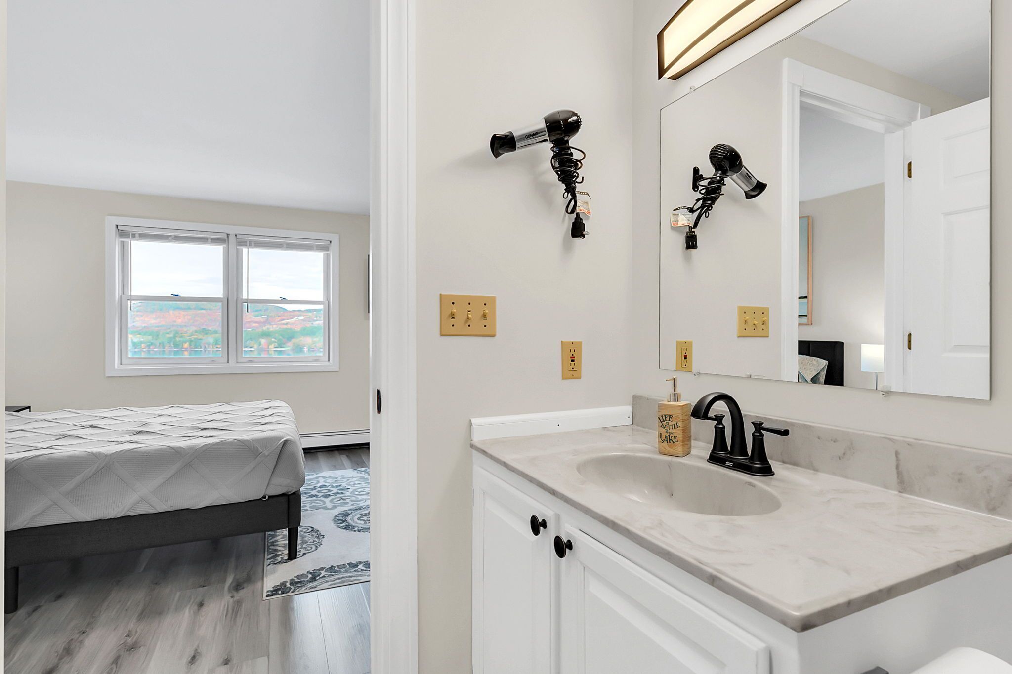 Un dormitorio moderno con cama, un baño con lavamanos y espejo, y una ventana con vistas.