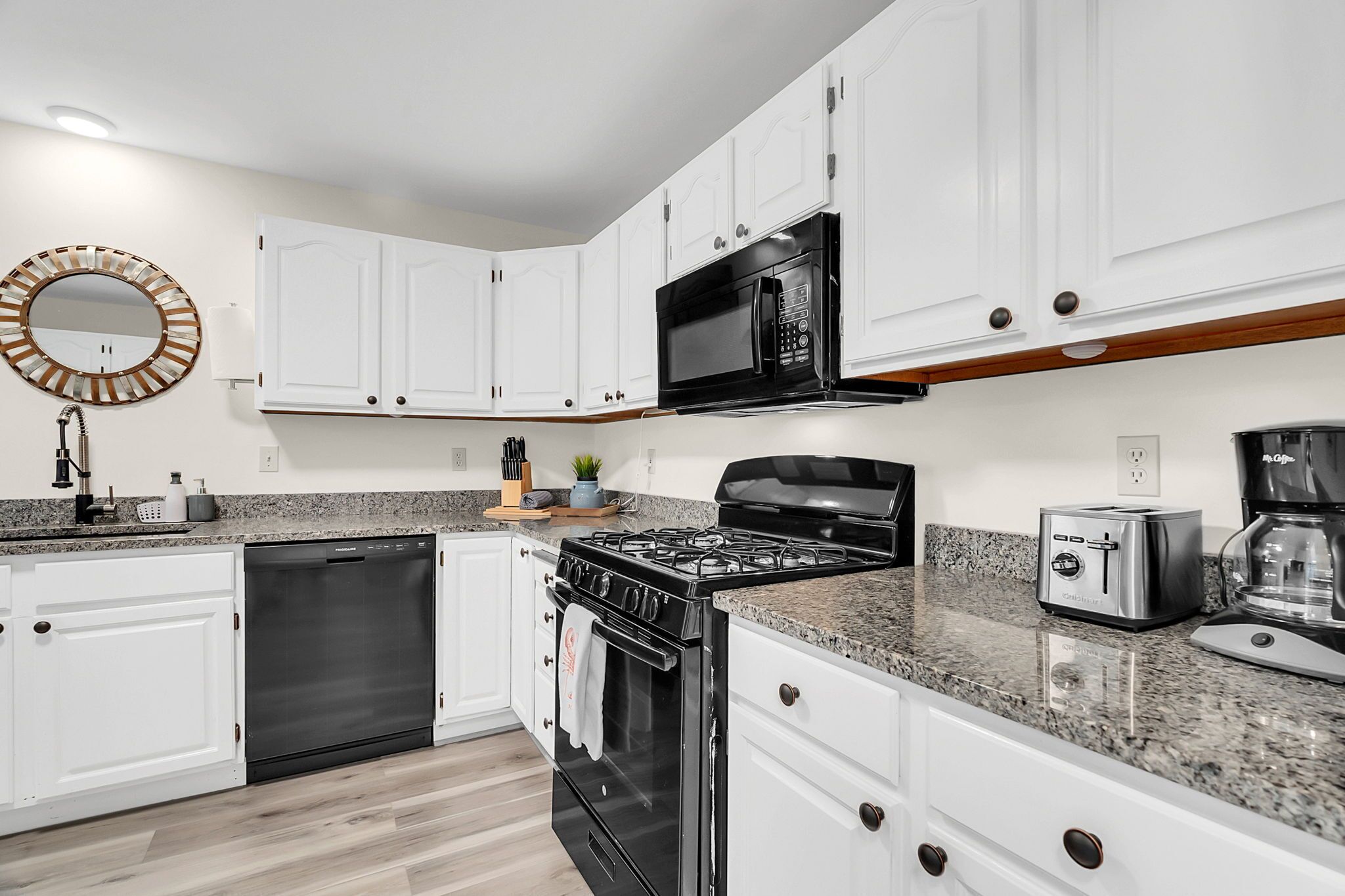 A modern kitchen with white cabinets, a stainless steel stove, a microwave, and a toaster.