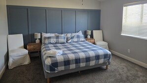 Camera da letto con un letto, due comodini, una sedia, una ventola a soffitto e una finestra con persiane.