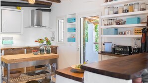 Una cocina moderna con vigas de madera, una campana extractora de acero inoxidable y una mesa de comedor de madera con un cuenco de fruta y jarrones.