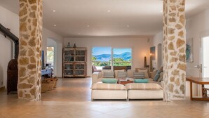 Un salón espacioso con un conjunto de sofás, una mesa de madera y vistas al exterior.