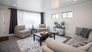 Un salon avec deux canapés, une table basse, une table d’appoint et une fenêtre avec des rideaux.