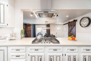 A modern kitchen with a central island, white cabinetry, and a large clock on the wall. - Salt Lake City - Rose Park Home Near Downtown & Airport | 3BR Modern Home (Salt Lake City)
