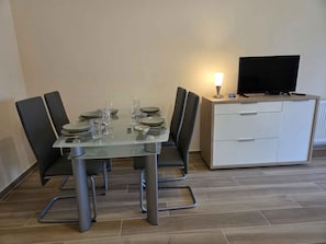 A dining table with chairs, a television, and a cabinet.