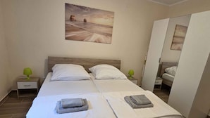 A double bed with white linens, two bedside tables with green lamps, a painting on the wall, and a wardrobe. - Holiday apartment with terrace and air conditioning (Novi Vinodolski)