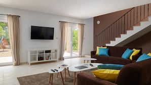 A modern living room with a sofa, coffee table, and TV. There is a staircase and a sliding door leading to an outdoor area. - Villa Sonia with private pool, 4 bedrooms and beautiful garden (Stari Grad)