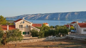 A coastal residential area with houses featuring red-tiled roofs and stone walls, surrounded by greenery and overlooking a body of water. - Villa Sonia with private pool, 4 bedrooms and beautiful garden (Stari Grad)