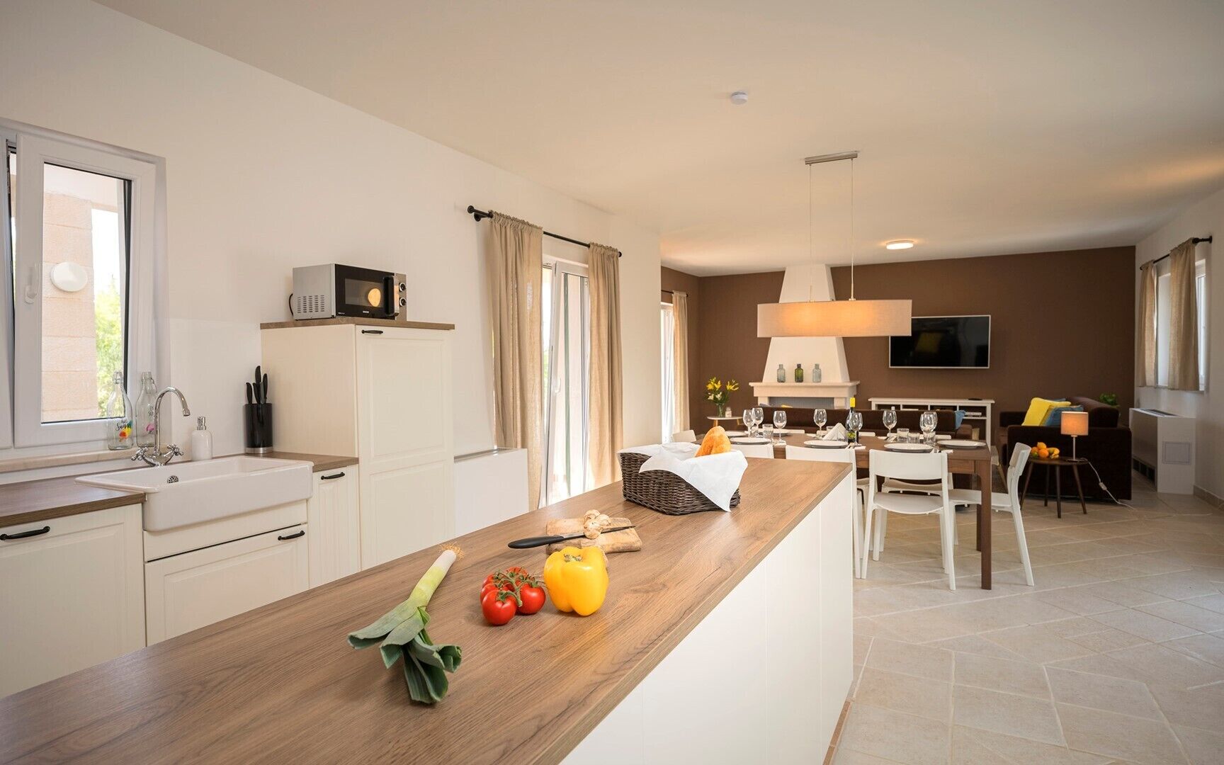 Una cocina moderna con encimera de madera, un lavamanos integrado y un comedor con mesa y sillas.