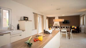 Eine moderne Küche mit Holztischplatte, eingebautem Spülbecken und einem Essbereich mit Tisch und Stühlen.