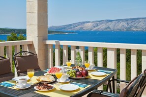 A table set with breakfast items including bread, fruit, and beverages, overlooking a scenic coastal view. - 4-bedroom Villa Erica with private pool and stunning sea view (Stari Grad)