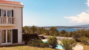 Un immeuble de deux étages doté d’un balcon, d’une piscine et offrant une vue sur la mer.