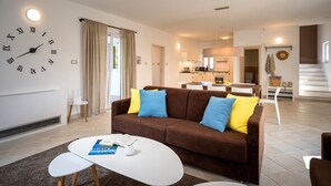 A modern living room with a brown sofa, a white coffee table, and a large wall clock. - Holiday villa Stella with private pool and 3 bedrooms (Stari Grad)
