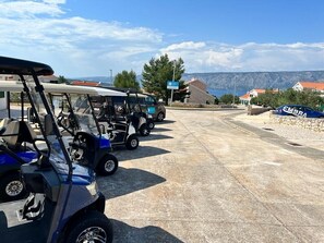 A parking area with golf carts and a stone wall with a sign.