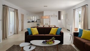 En moderne stue med en brun sofa, to sofaborde og en skål med frugt.
